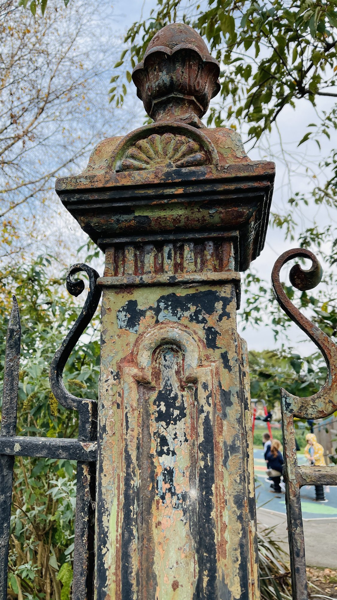A 1914 cast-iron railing post in Belle Vue Park, layers of old paint peeling to rust