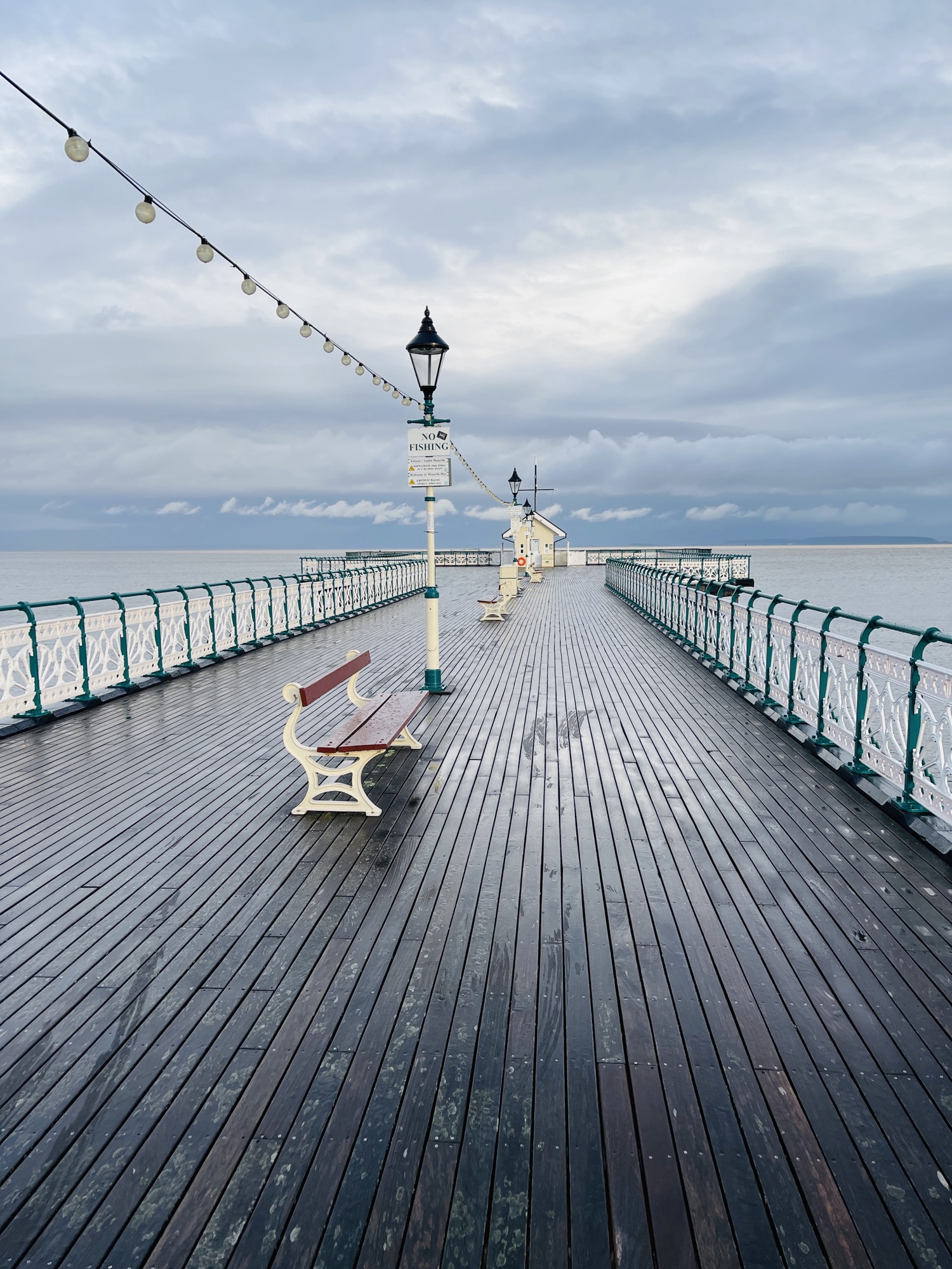 Wet boards and railings on Penarth Pier under a grey sky