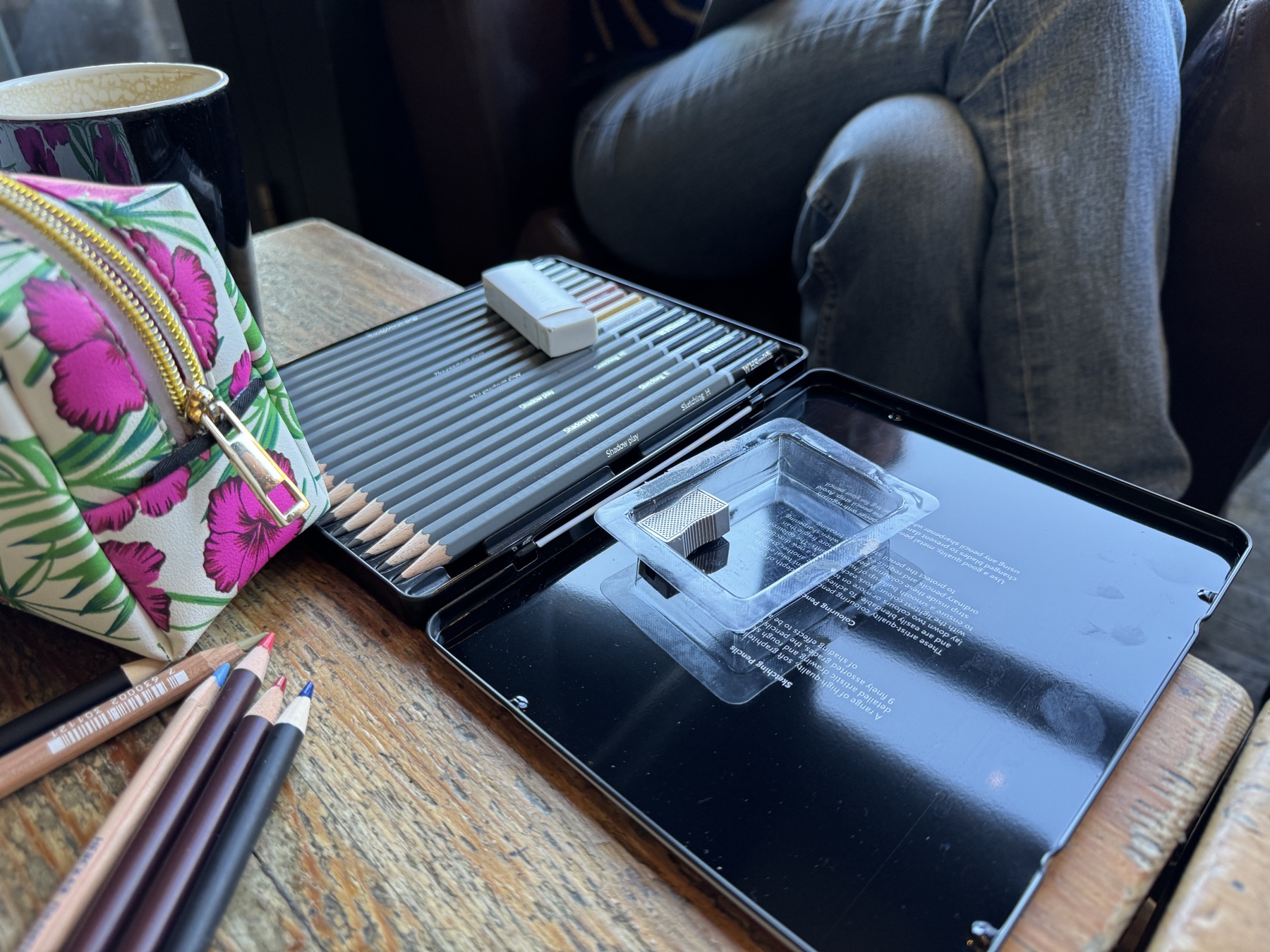 Graphite pencils and sharpener in a tin on a cafe table