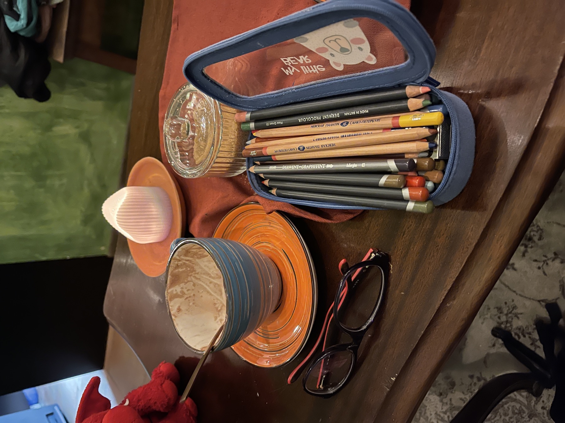 Sketchbook and pencil case beside coffee on a cafe table