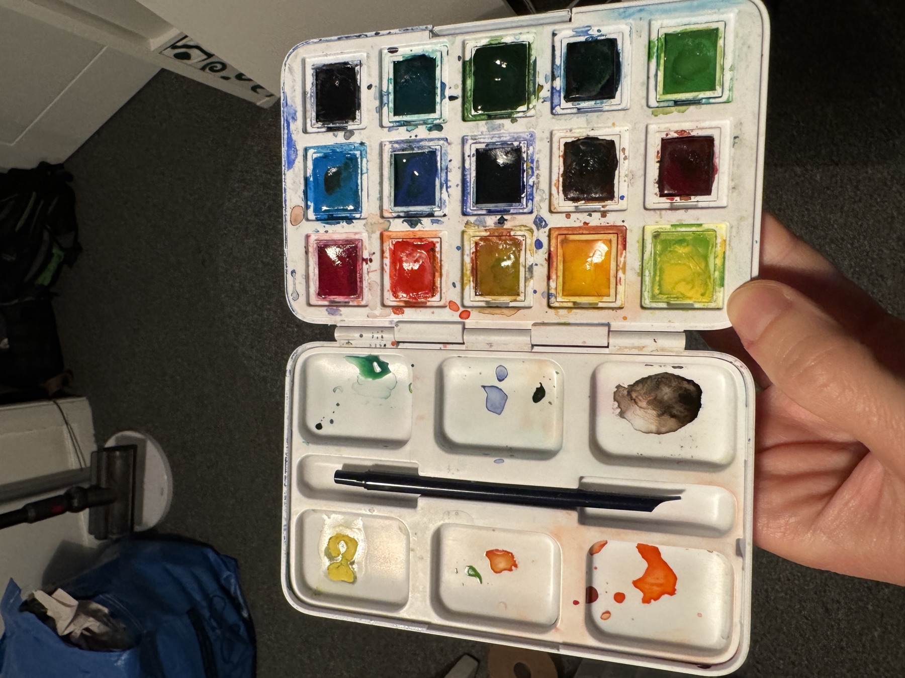 Small watercolour palette held open with bright paint pans