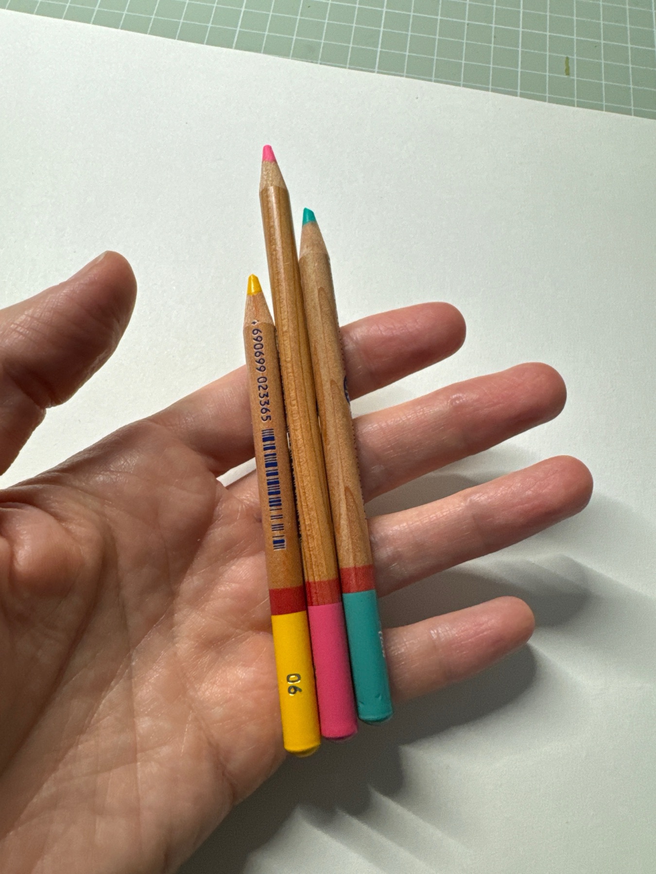 Three short coloured pencils held in one hand
